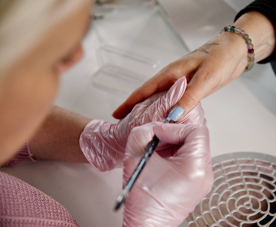 Karin lackiert einen Nagel mit blauem Lack